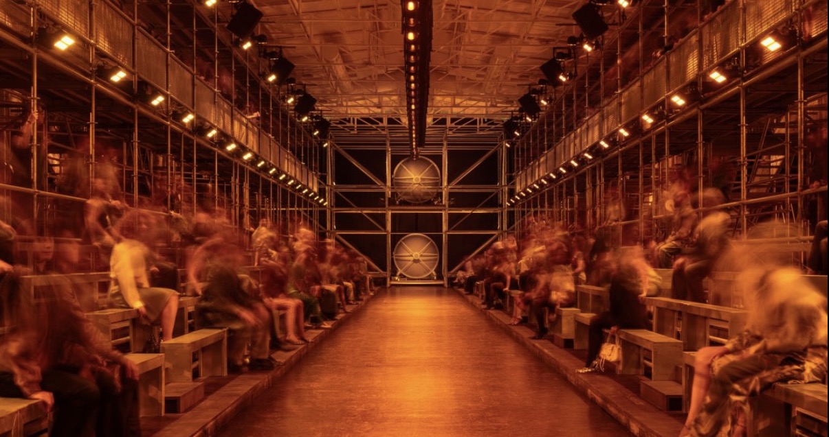 Escenografía y público del desfile Diesel SS27 en Milán, bajo luces anaranjadas